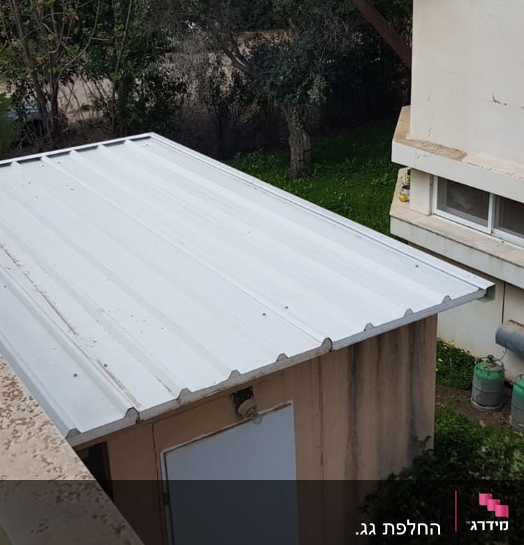 גג מתכת לבן על מבנה קטן בחצר